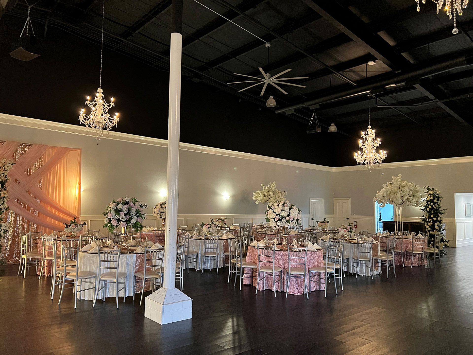 A large room with tables and chairs set up for a wedding reception