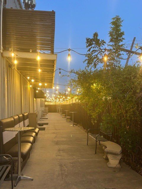 Outdoor patio with string lights, seating, and a concrete path.