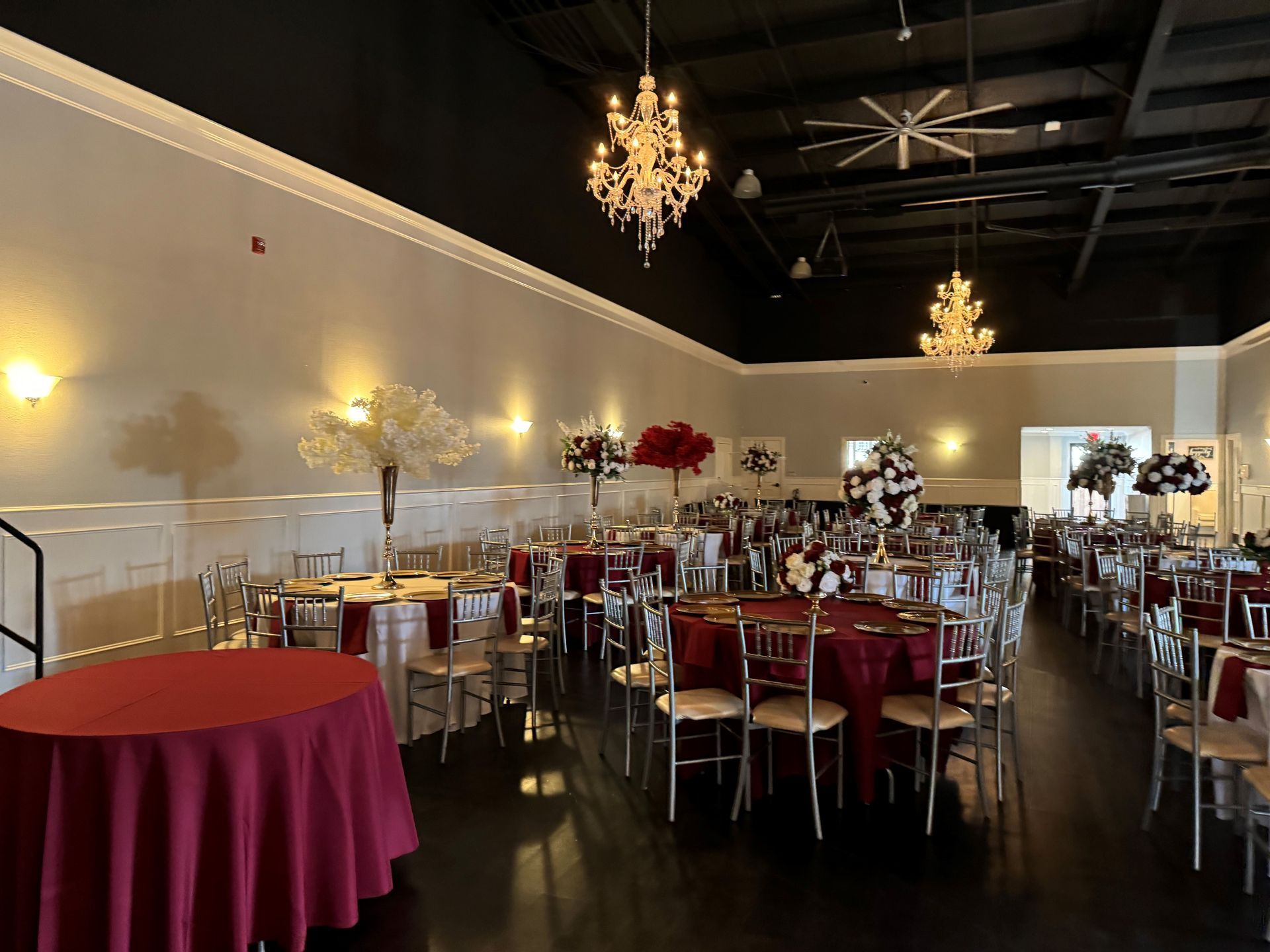 A large room with tables and chairs set up for a wedding reception