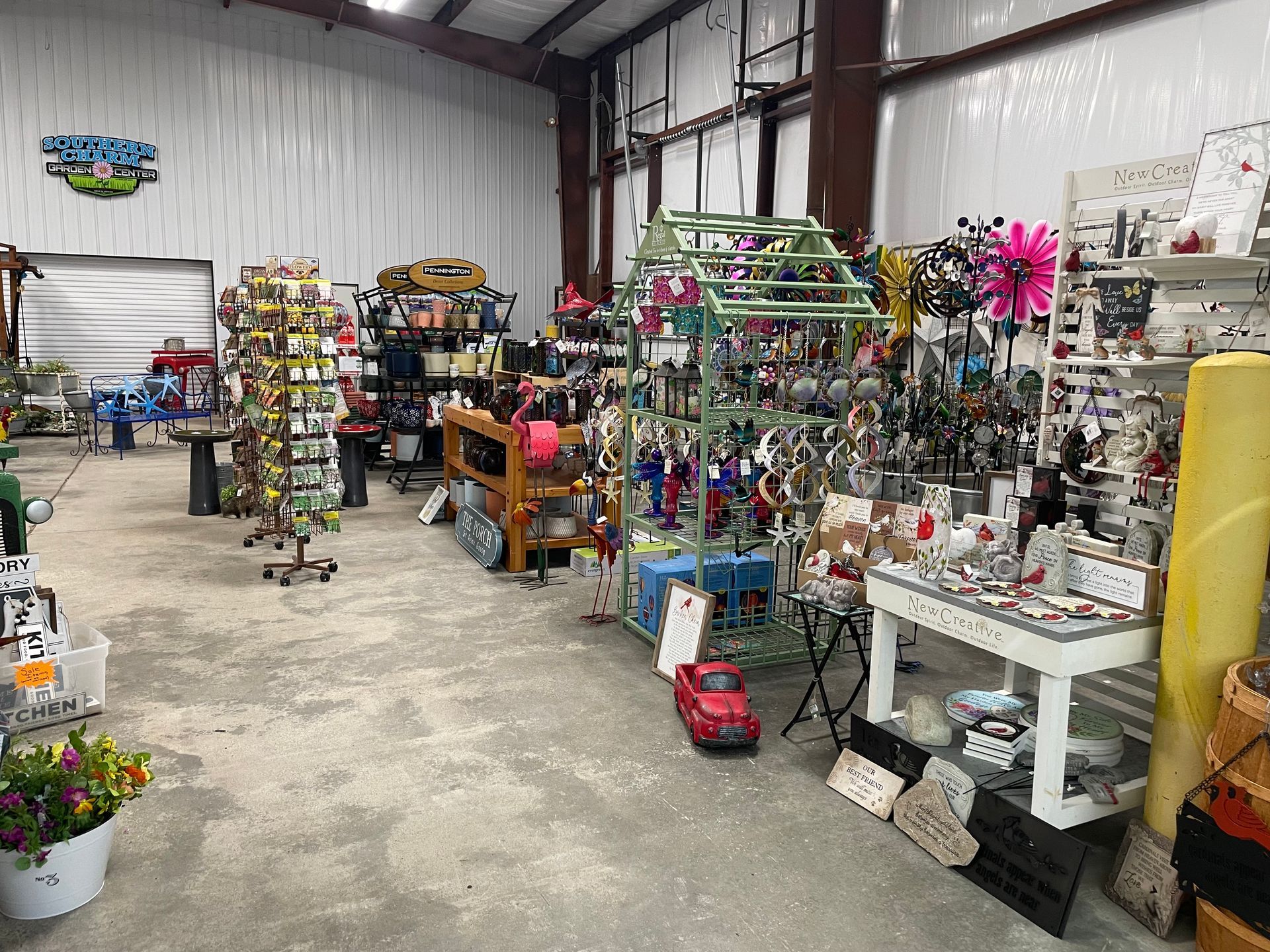 Indoor gift shop aisle with shelves of colorful decorations and plants in a warehouse-style space
