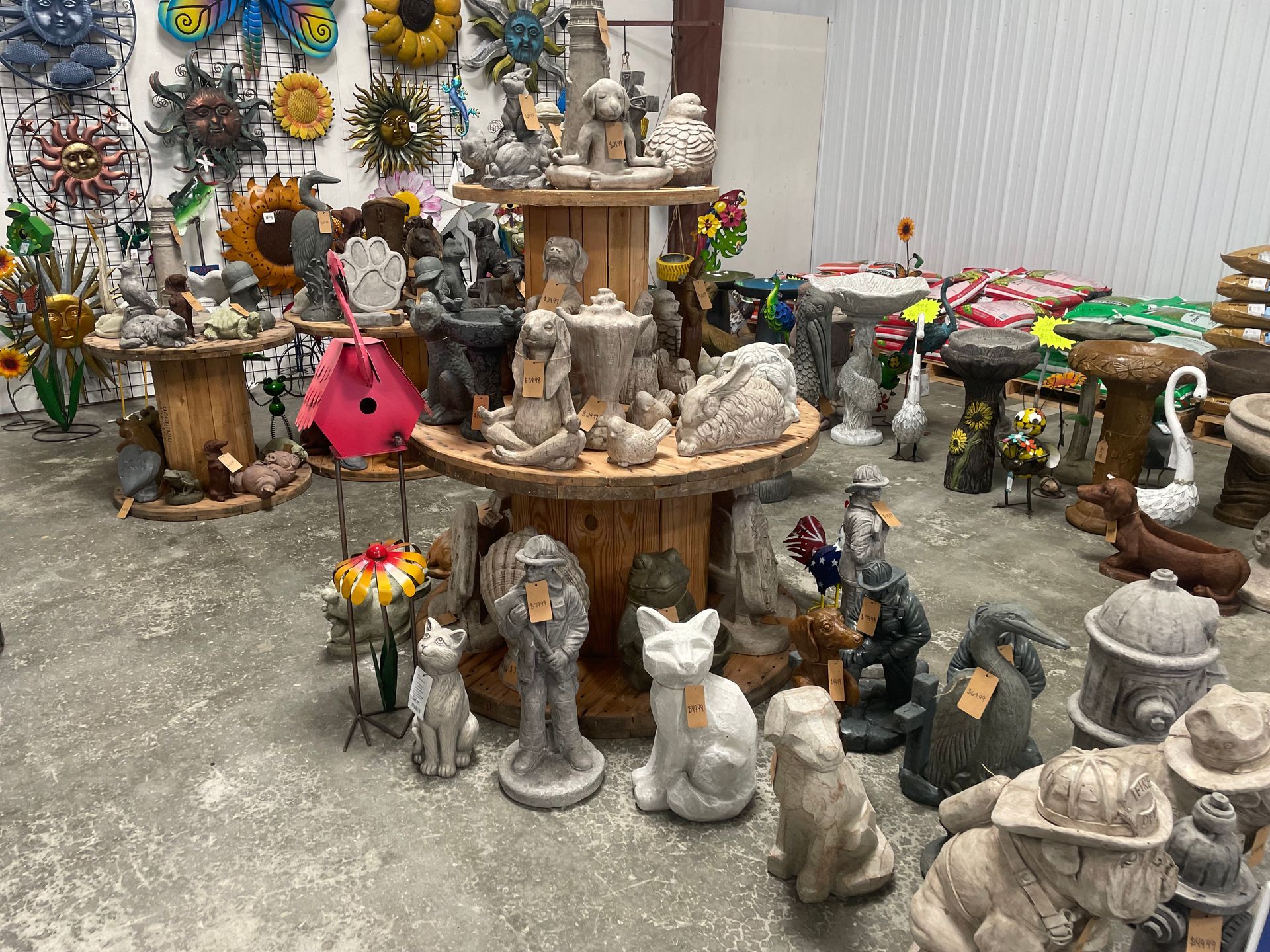 Rows of colorful garden statues and figurines displayed on shelves and tables in a shop