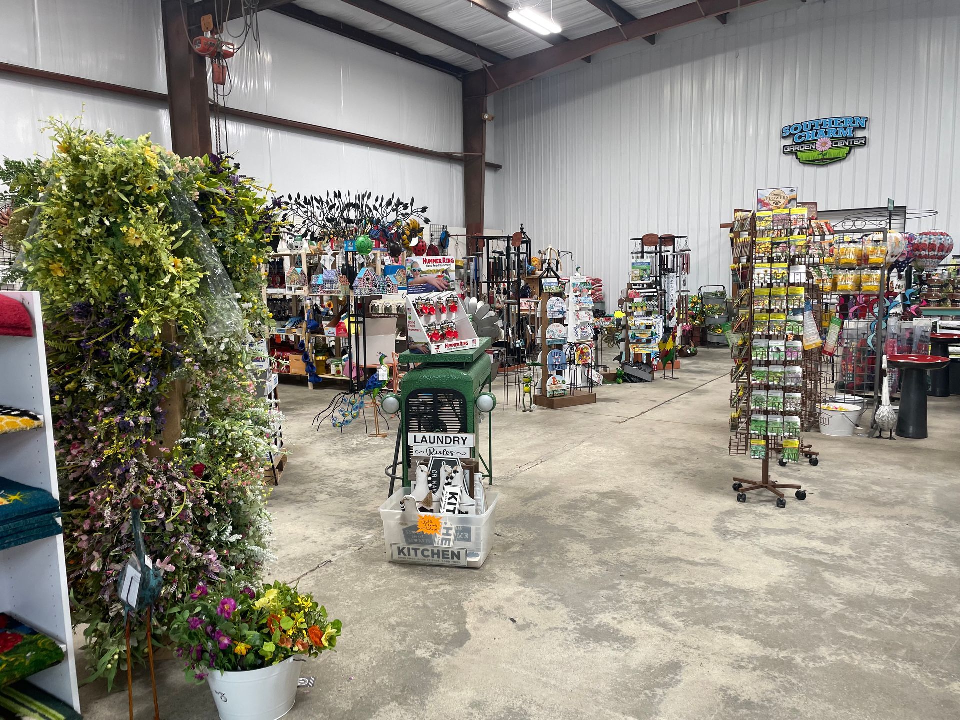 Indoor garden center aisle with racks of colorful plants and decor in a warehouse-style store