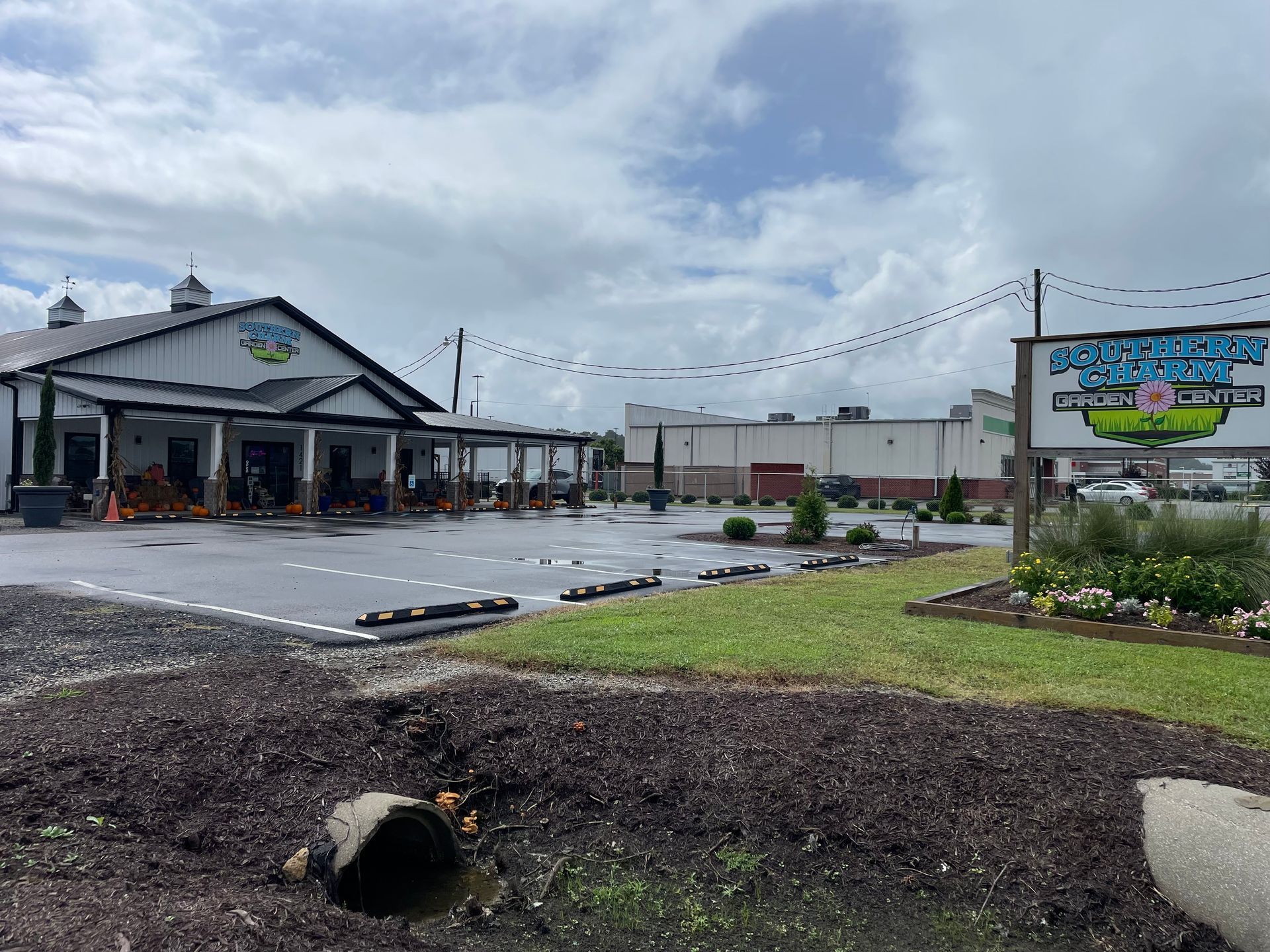 Small roadside building and sign beside a wet parking lot under a cloudy sky