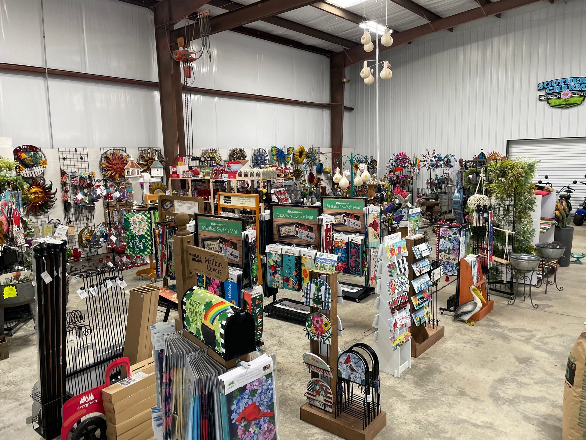 Indoor shop filled with colorful garden decor, wind chimes, and shelves of merchandise in a warehouse space
