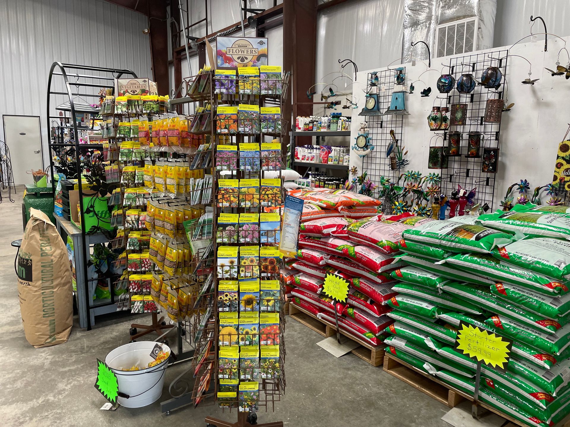 Hardware store aisle with stacked bags, hanging tools, and shelves of colorful supplies