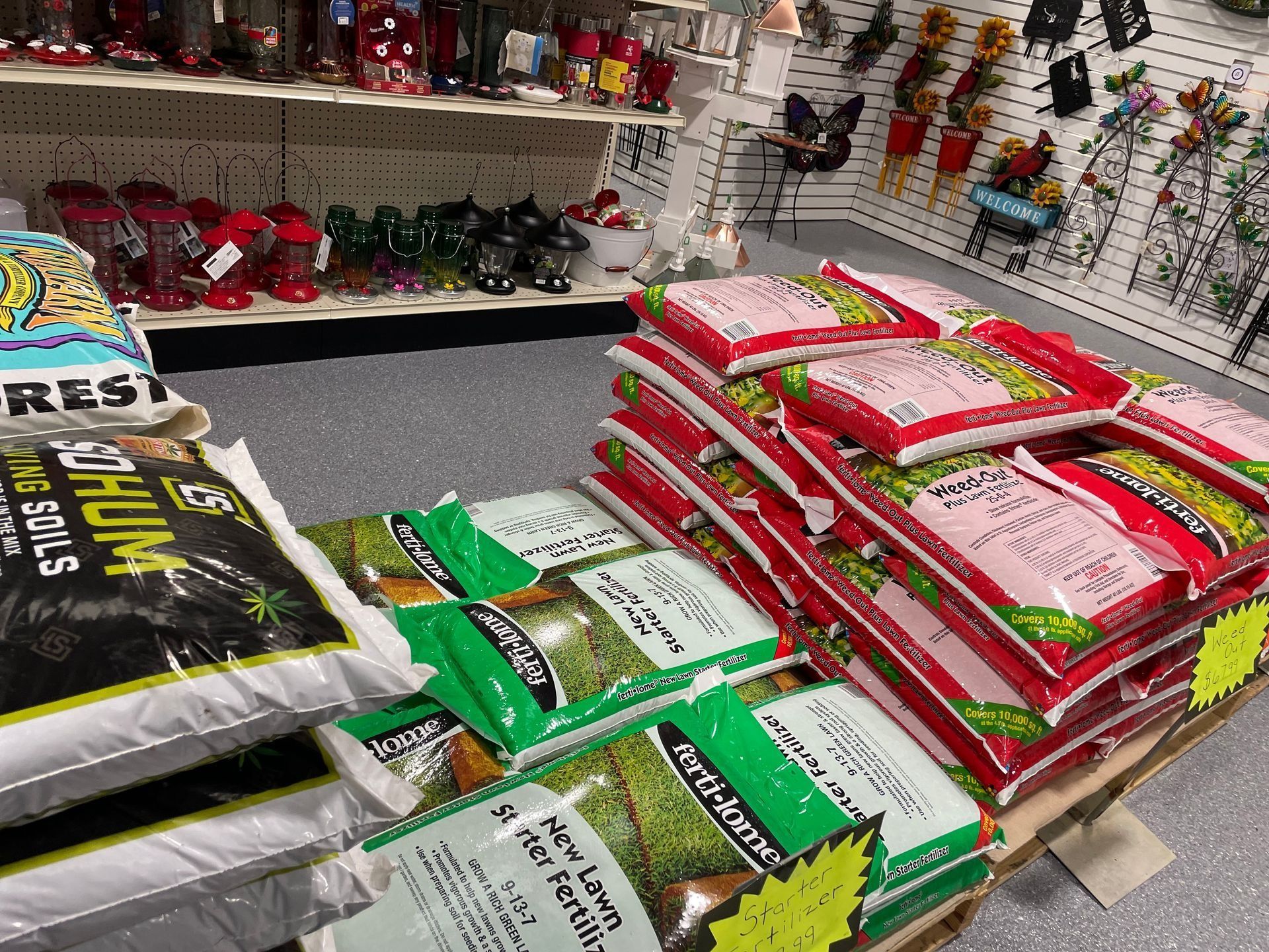 Stacked bags of fertilizer in a store aisle, with red, green, and black packaging on display.