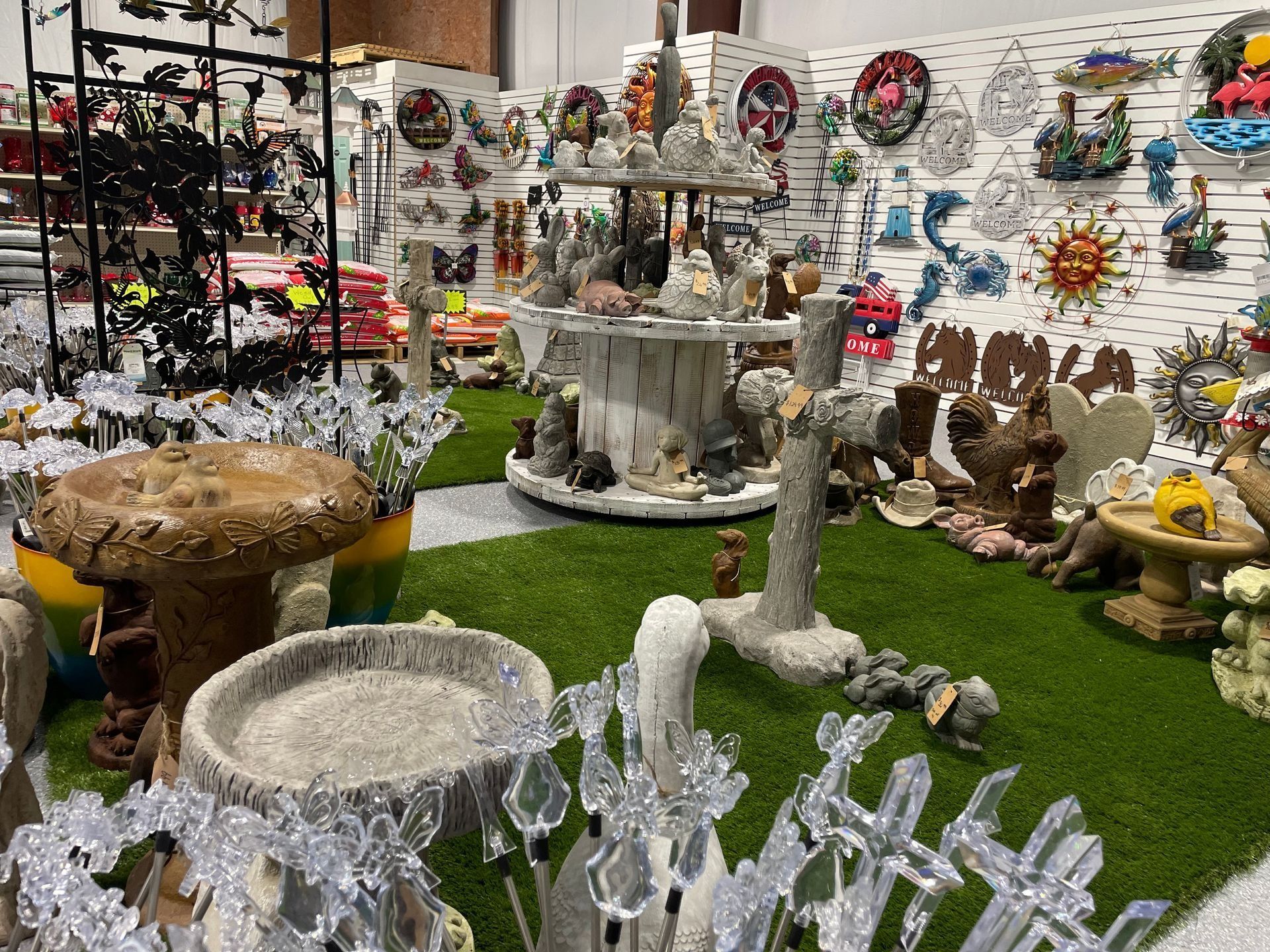 Indoor display of decorative garden ornaments, fountains, and wreaths on artificial grass