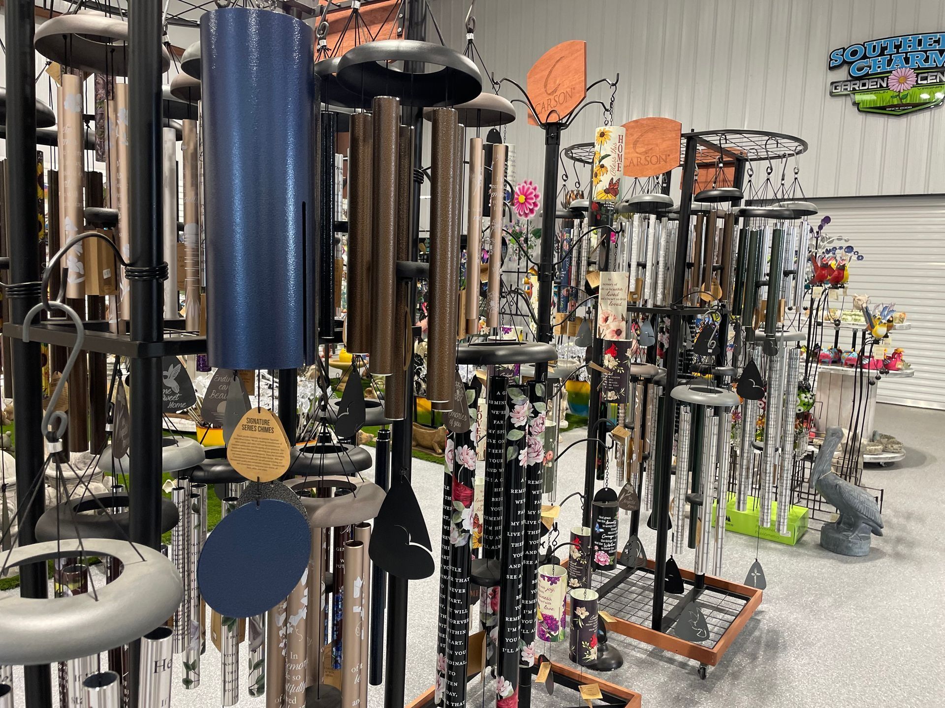 Store display of colorful hanging wind chimes and garden ornaments in a shop aisle