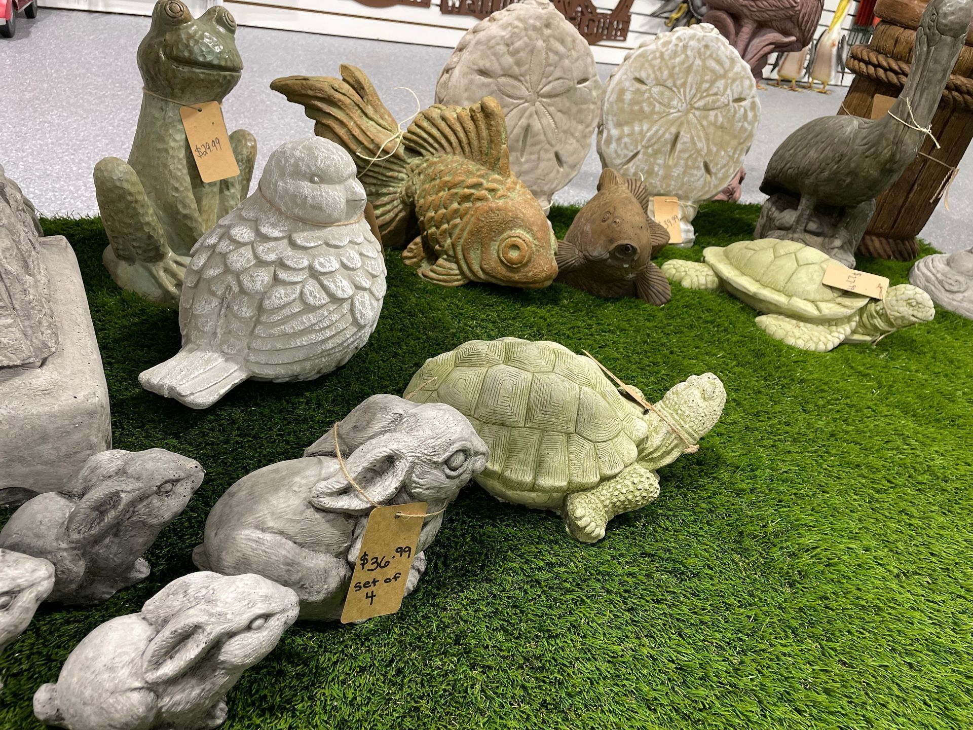 Stone turtle sculptures displayed on artificial grass, some with tags attached