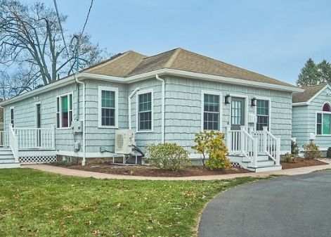 Person using a knife to cut asphalt roof shingles during installation.