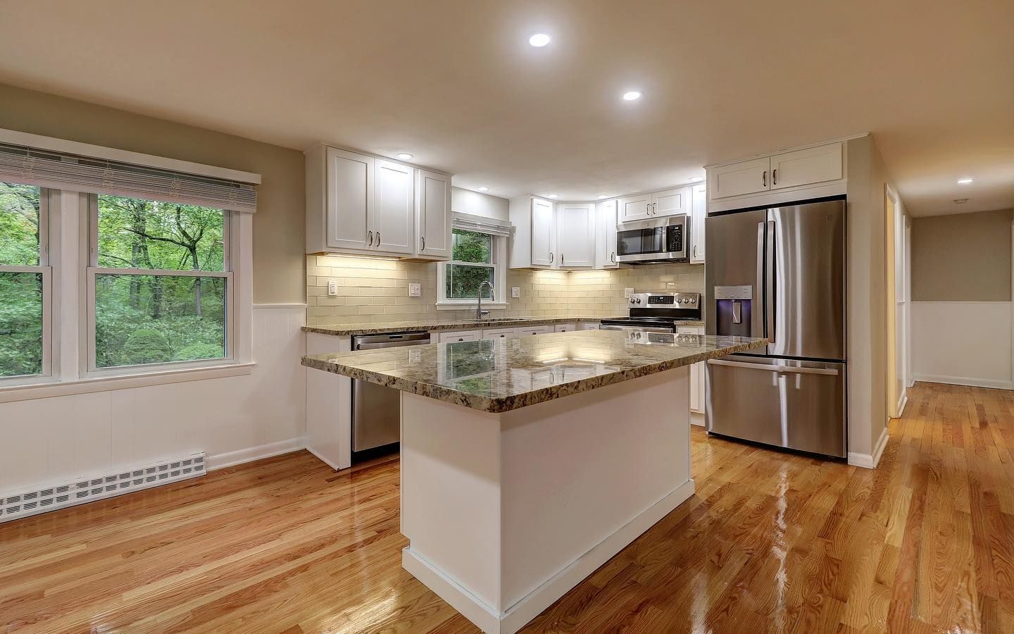Modern kitchen with white cabinets, stainless steel appliances, and granite countertop island.