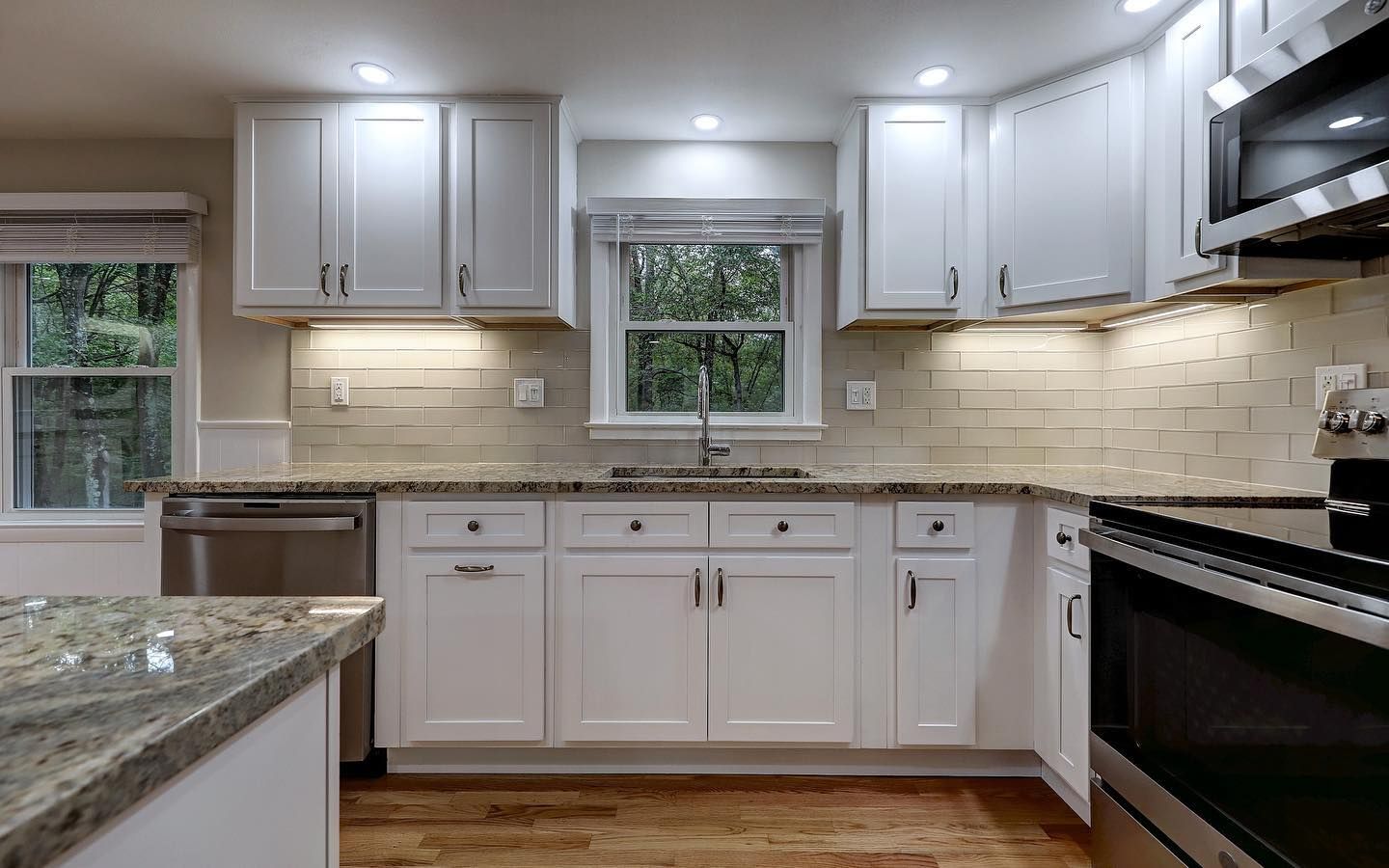 White kitchen with cabinets, stainless steel appliances, and a window.