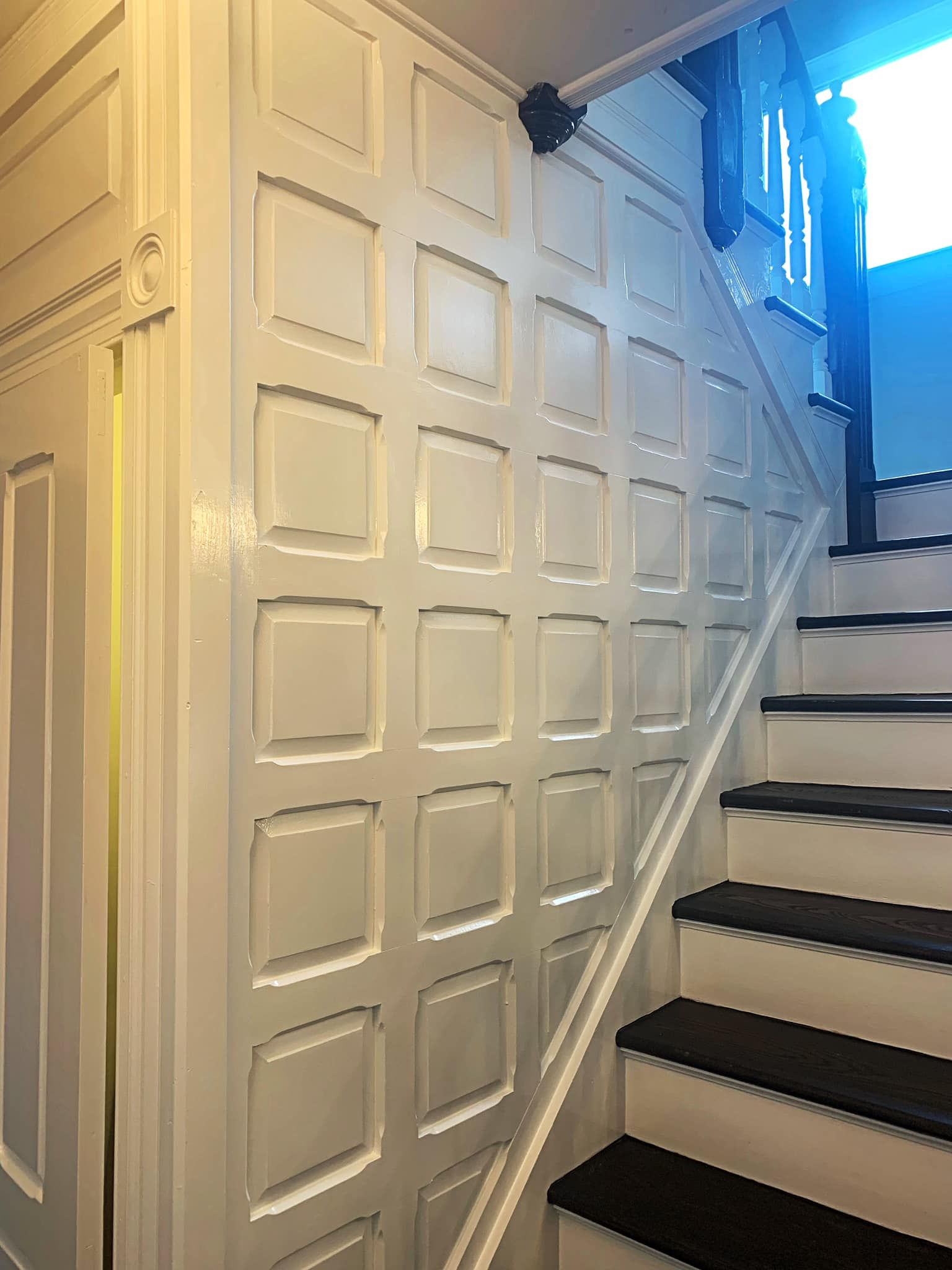 White paneled wall and staircase with black steps and white risers.