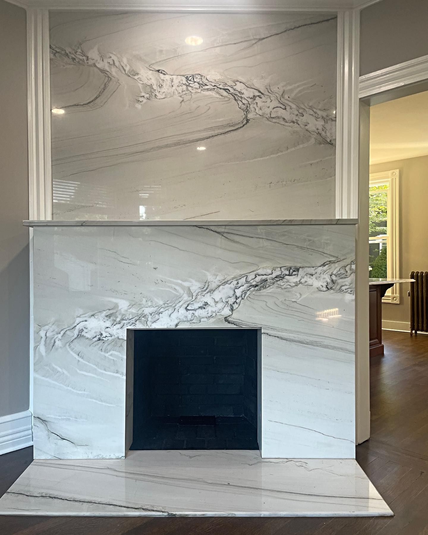 White marble fireplace with dark opening and patterned stone.