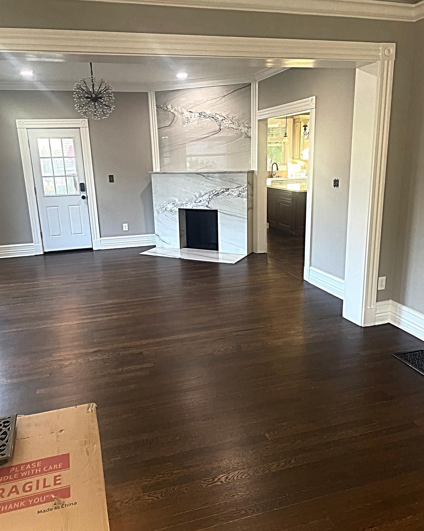 Living room with dark wood floors, fireplace, and doorway leading to a kitchen.