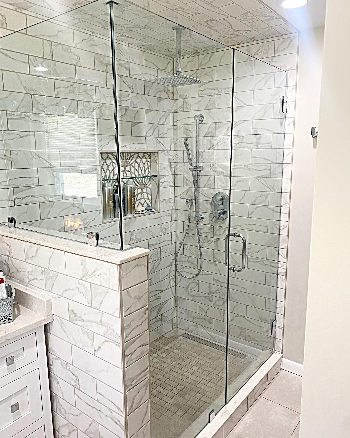 Modern bathroom with a glass shower enclosure and white tiled walls.