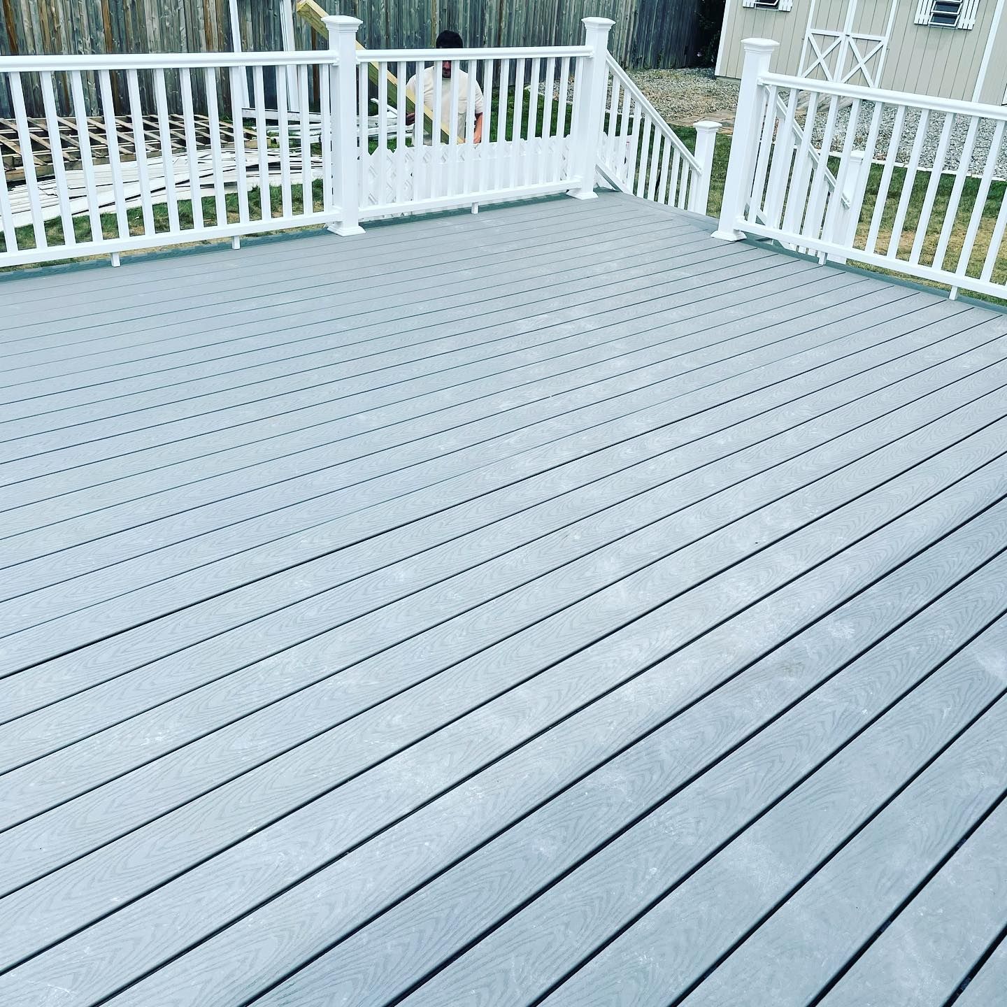 Gray composite deck with white railing in a backyard setting.