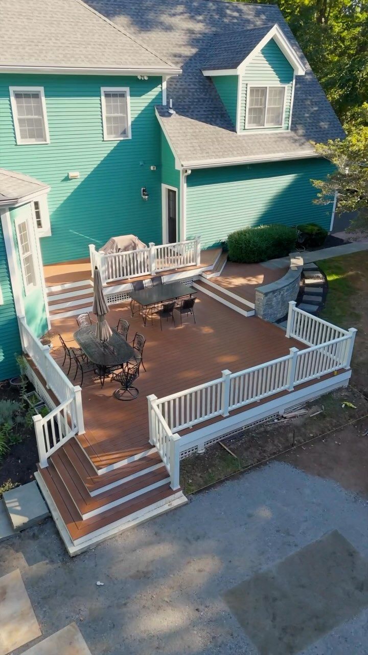Exterior of a green house with a multi-level wooden deck with white railing.