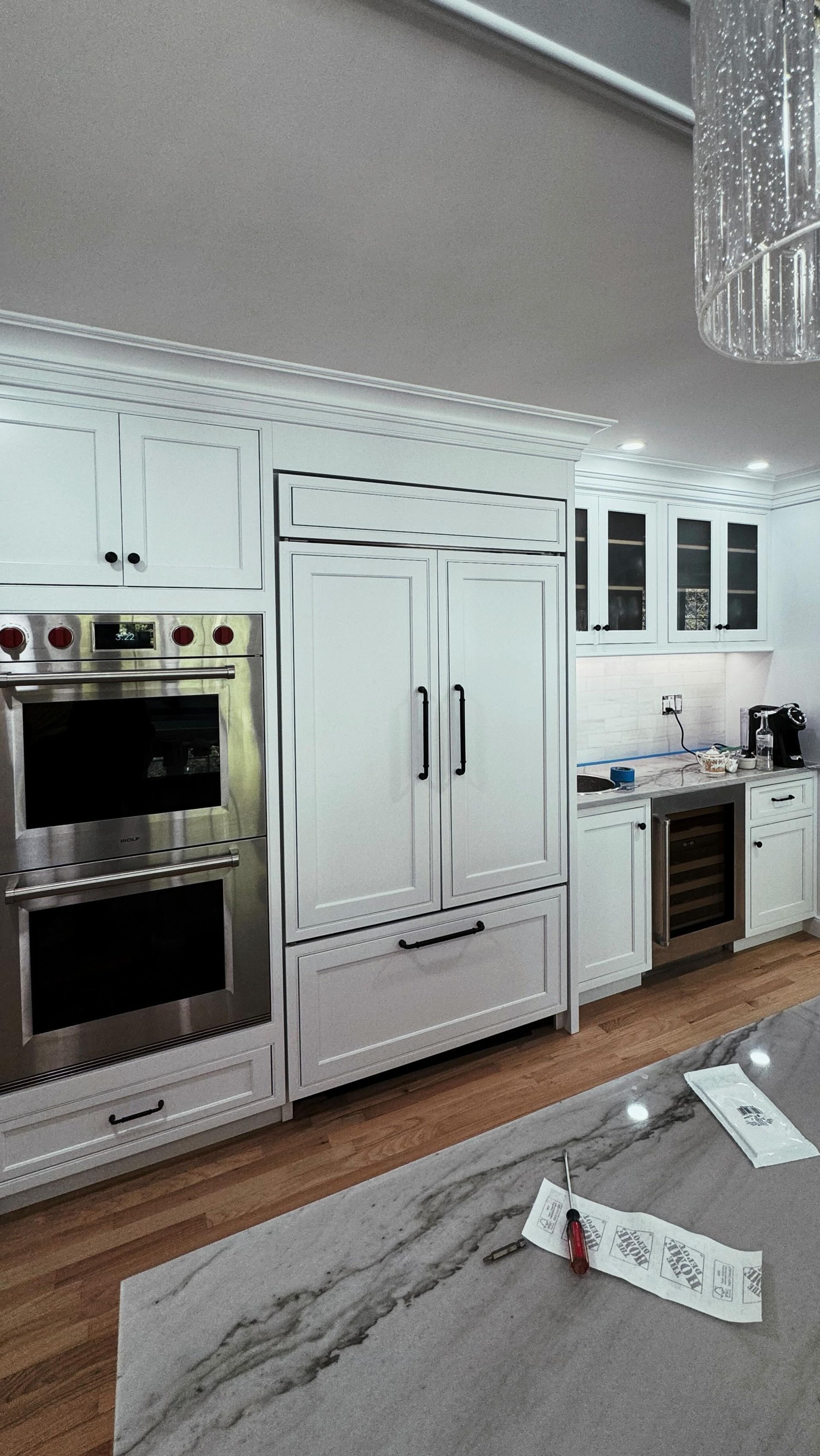 White kitchen with stainless steel appliances, marble countertop, and white cabinetry.