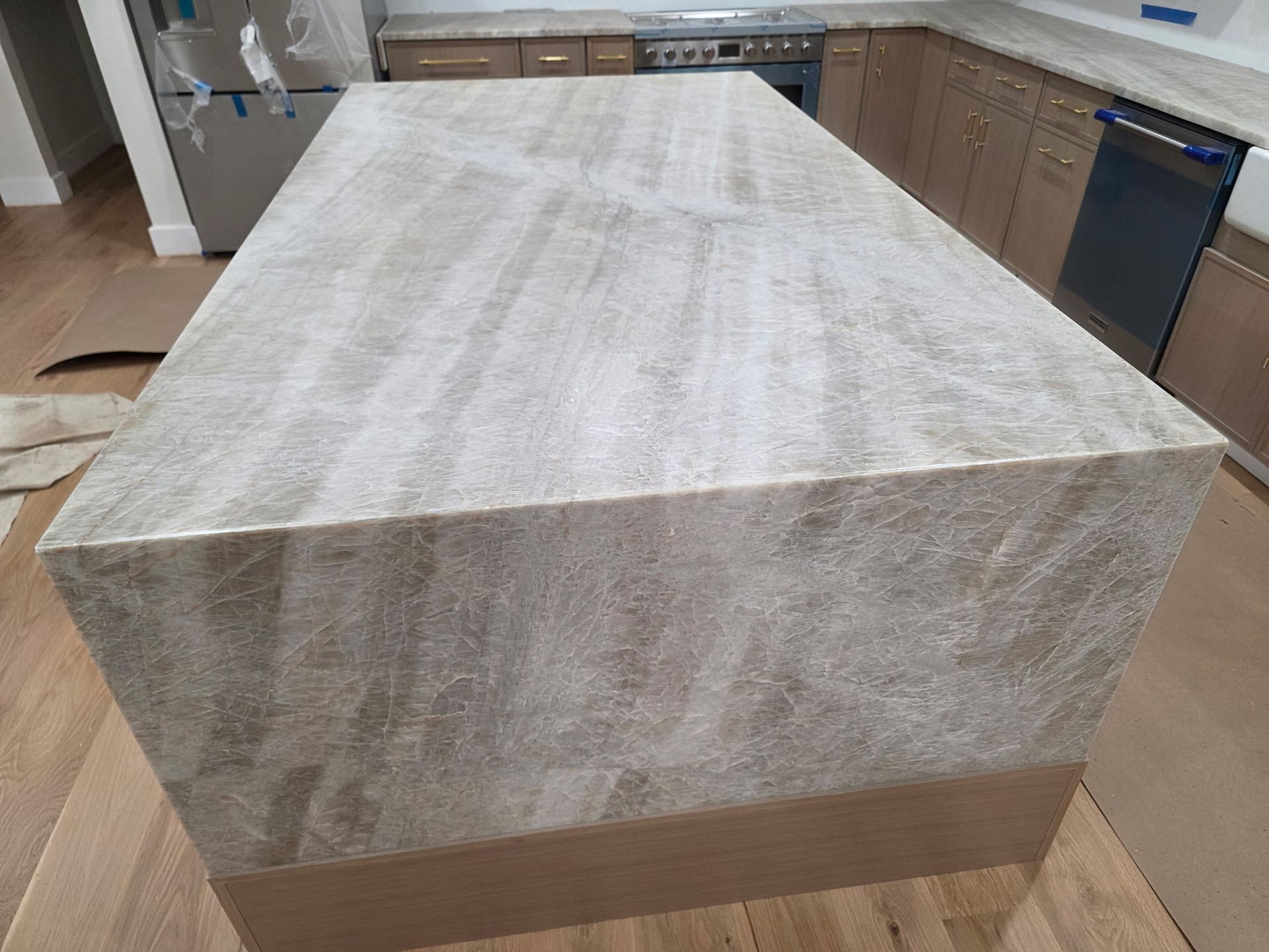 Kitchen island with a light-colored countertop covered in protective wrap. Cabinets and appliances are in the background.