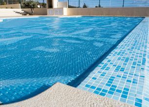Blue pool cover on a pool with blue and white tile border.