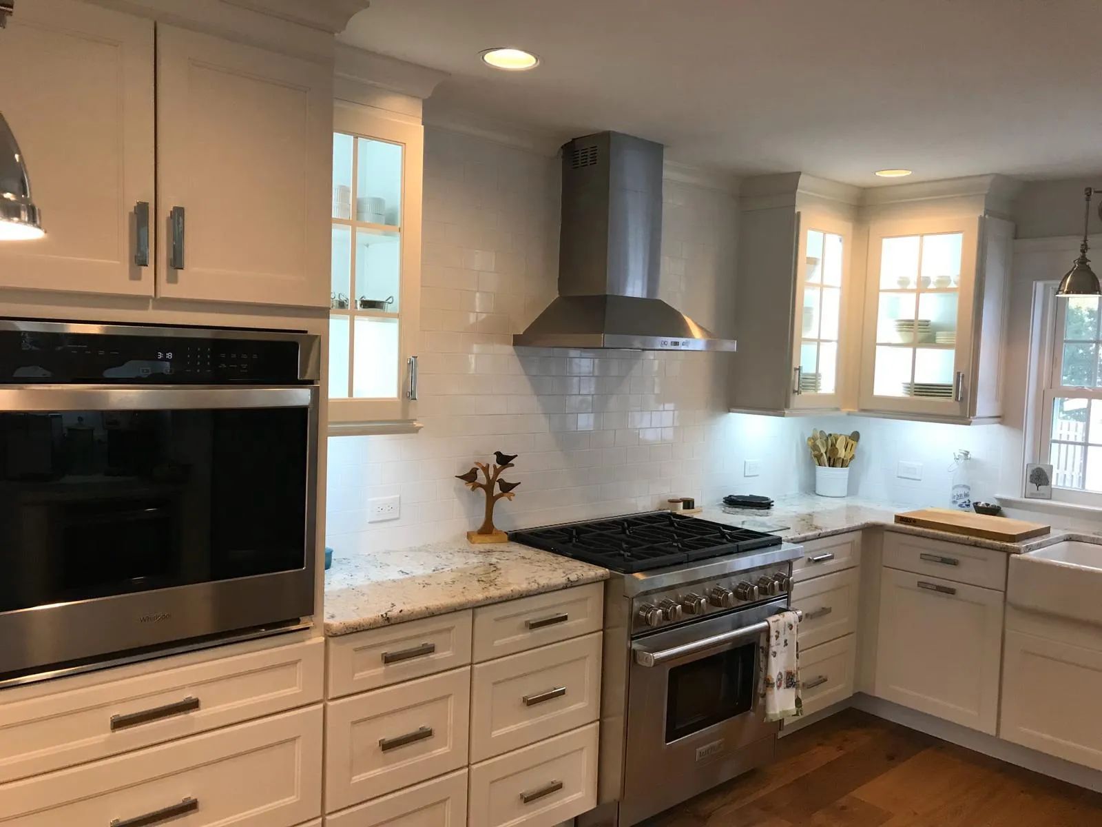 Bright modern kitchen with white cabinets, granite counters, stainless steel appliances, and a gas range.