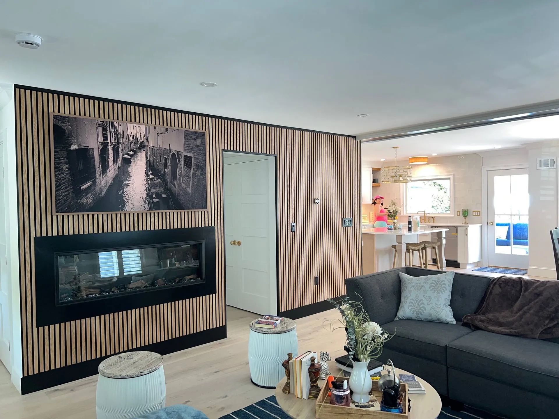 Modern living room with striped accent wall, wall-mounted TV, gray sectional sofa, and coffee table
