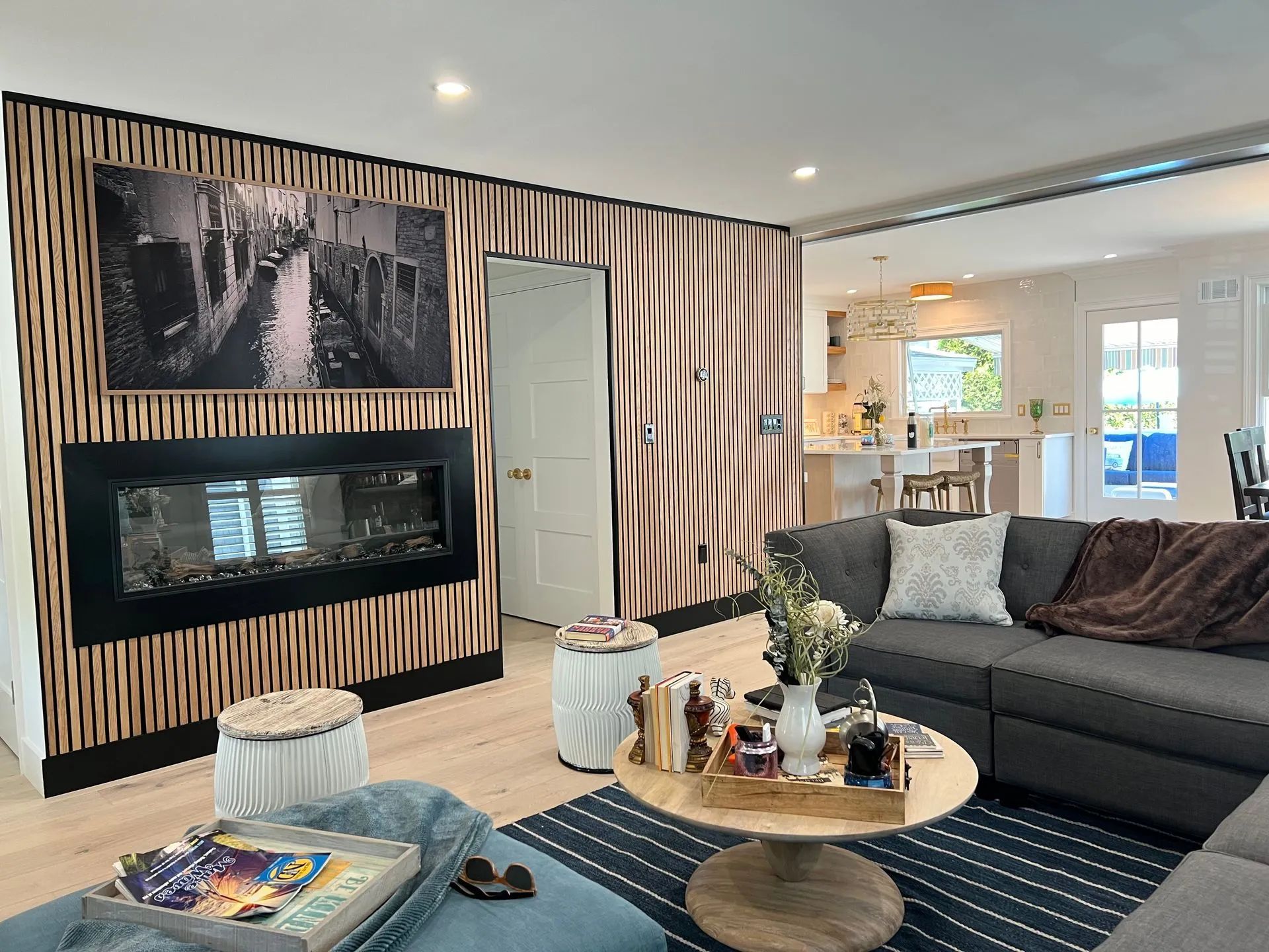 Modern living room with striped accent wall, fireplace, gray sectional, and round coffee table