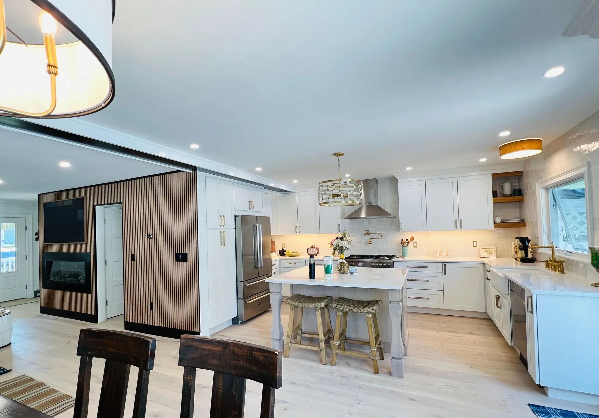 Bright modern kitchen and dining area with white cabinets, island, and light wood floors