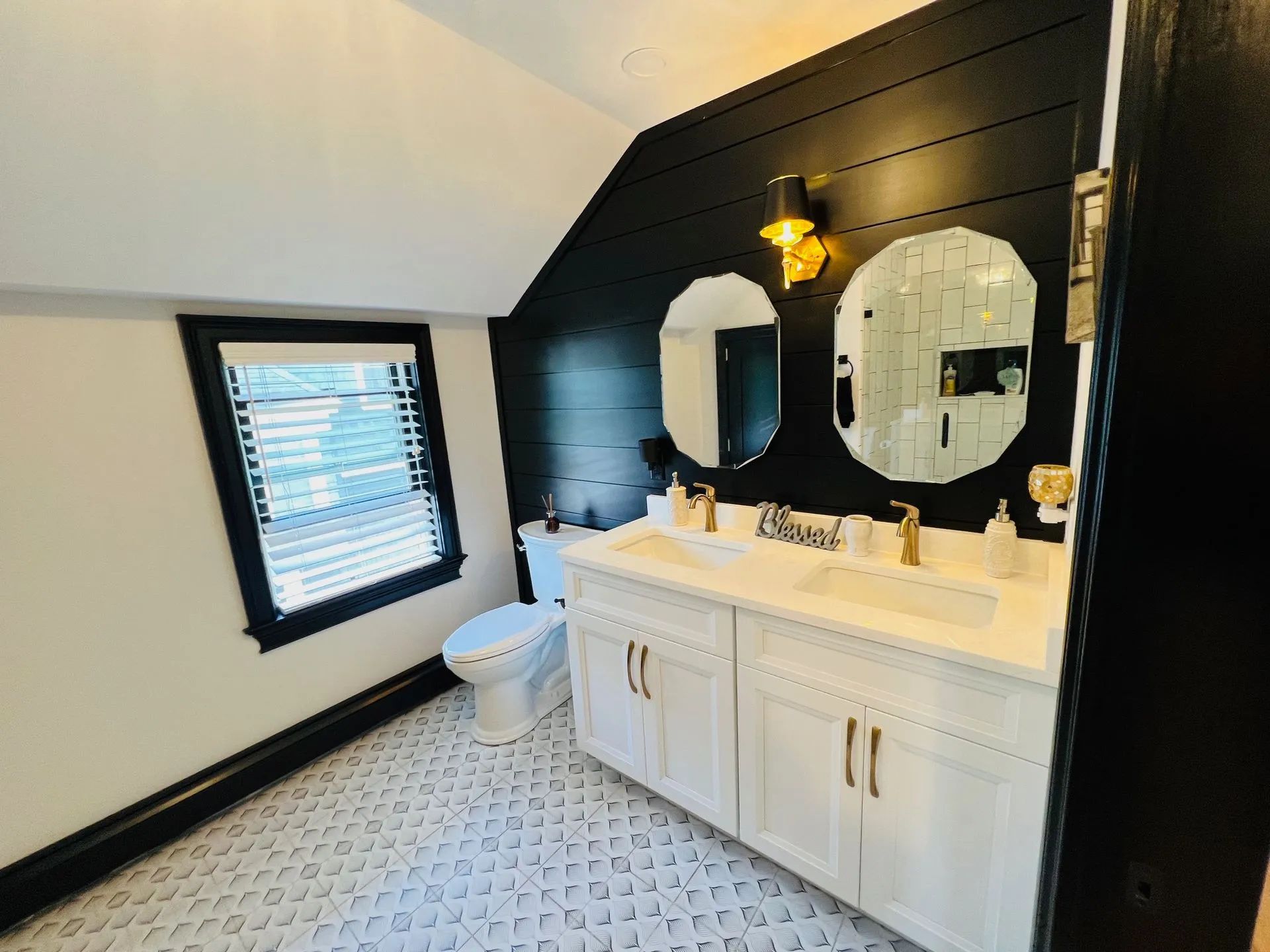 Black-and-white bathroom with vanity, twin mirrors, toilet, and patterned tile floor