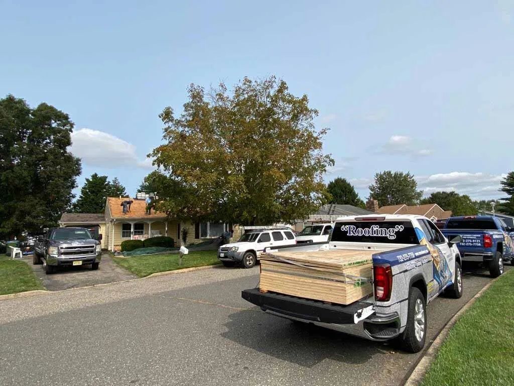 Pickup truck loaded with plywood parked on a suburban street with several other vehicles nearby
