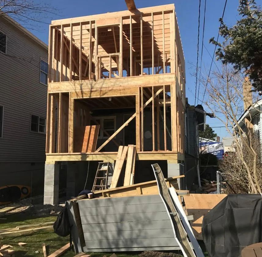 Partially built wooden house frame at a construction site with lumber and debris in front