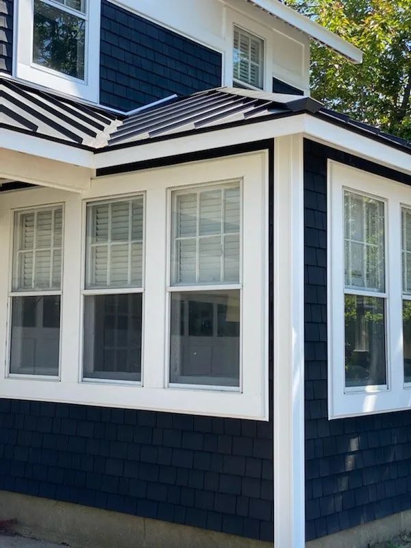 Blue house exterior with white-trimmed windows and dark shingle siding