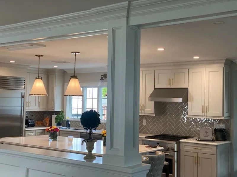 Bright white kitchen and dining area with pendant lights, island, and stainless-steel appliances