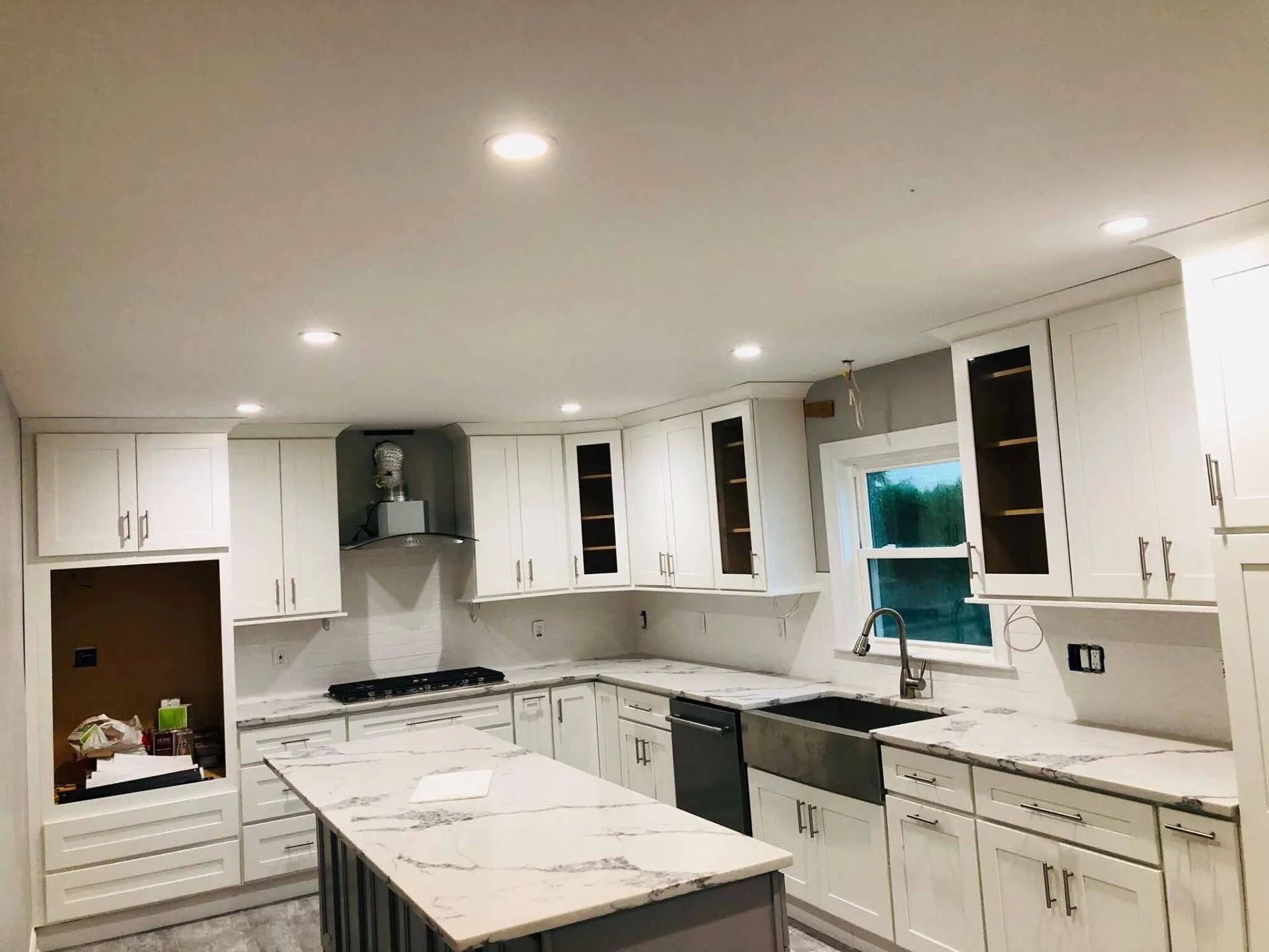 Bright white modern kitchen with marble island, white cabinets, and black appliances