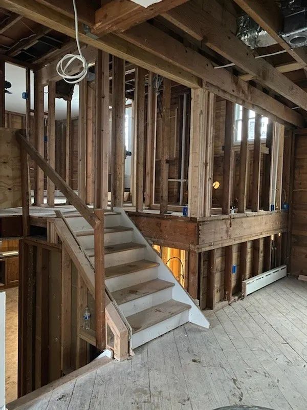 Unfinished interior with exposed framing and a wooden staircase under construction