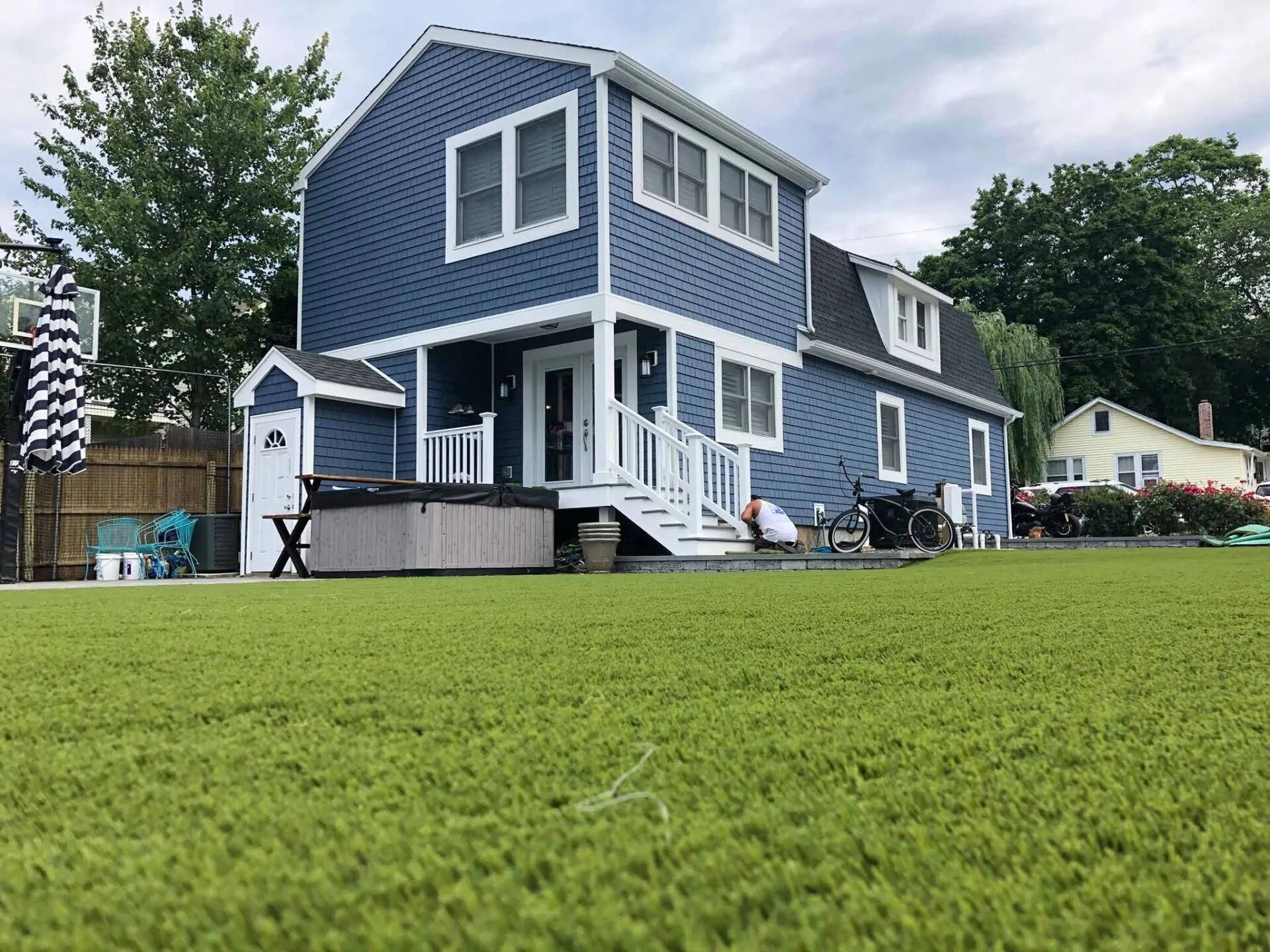 Blue two-story house with white trim and a green lawn in the foreground