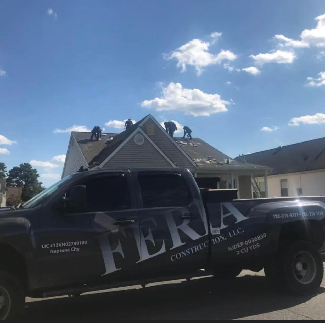 Black pickup truck with FBRA logo parked in front of a house under a bright blue sky