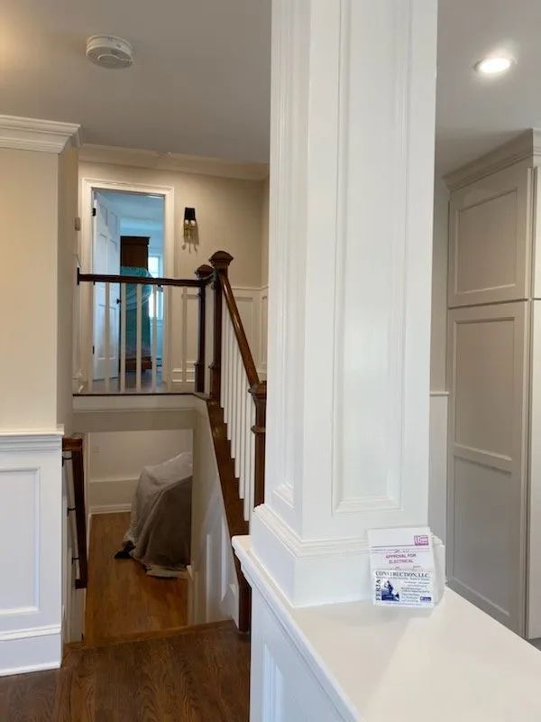 Stairwell and hallway interior with white trim, wood handrail, and recessed ceiling lights