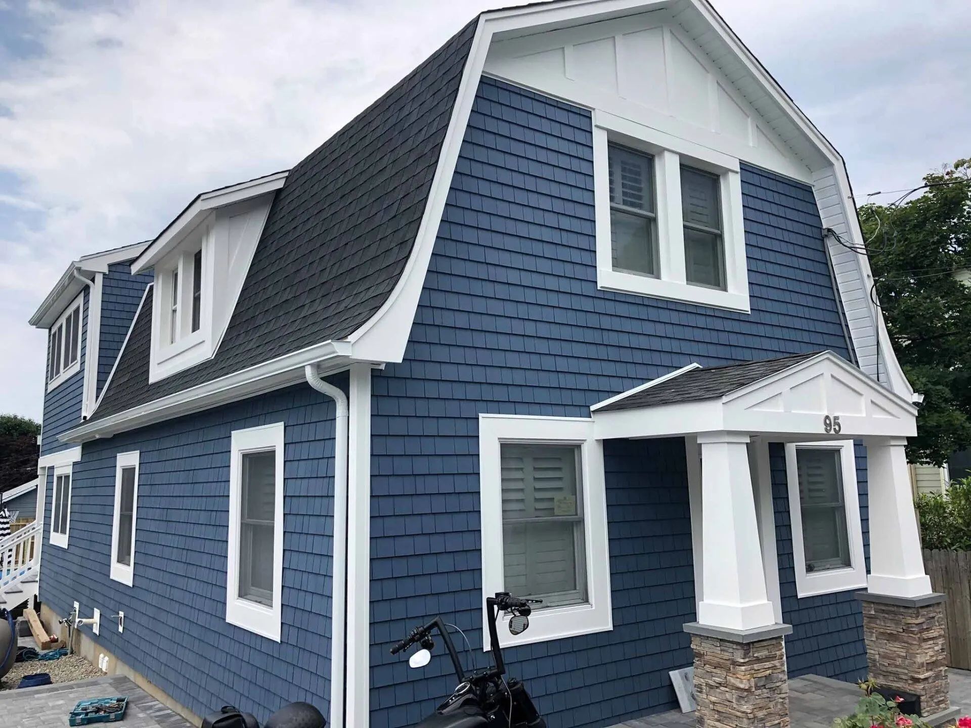 Blue two-story house with white trim, steep roof, and small front porch