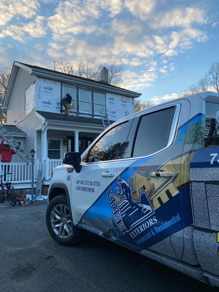 Decorated blue-and-white utility truck parked beside a house with holiday lights at dusk