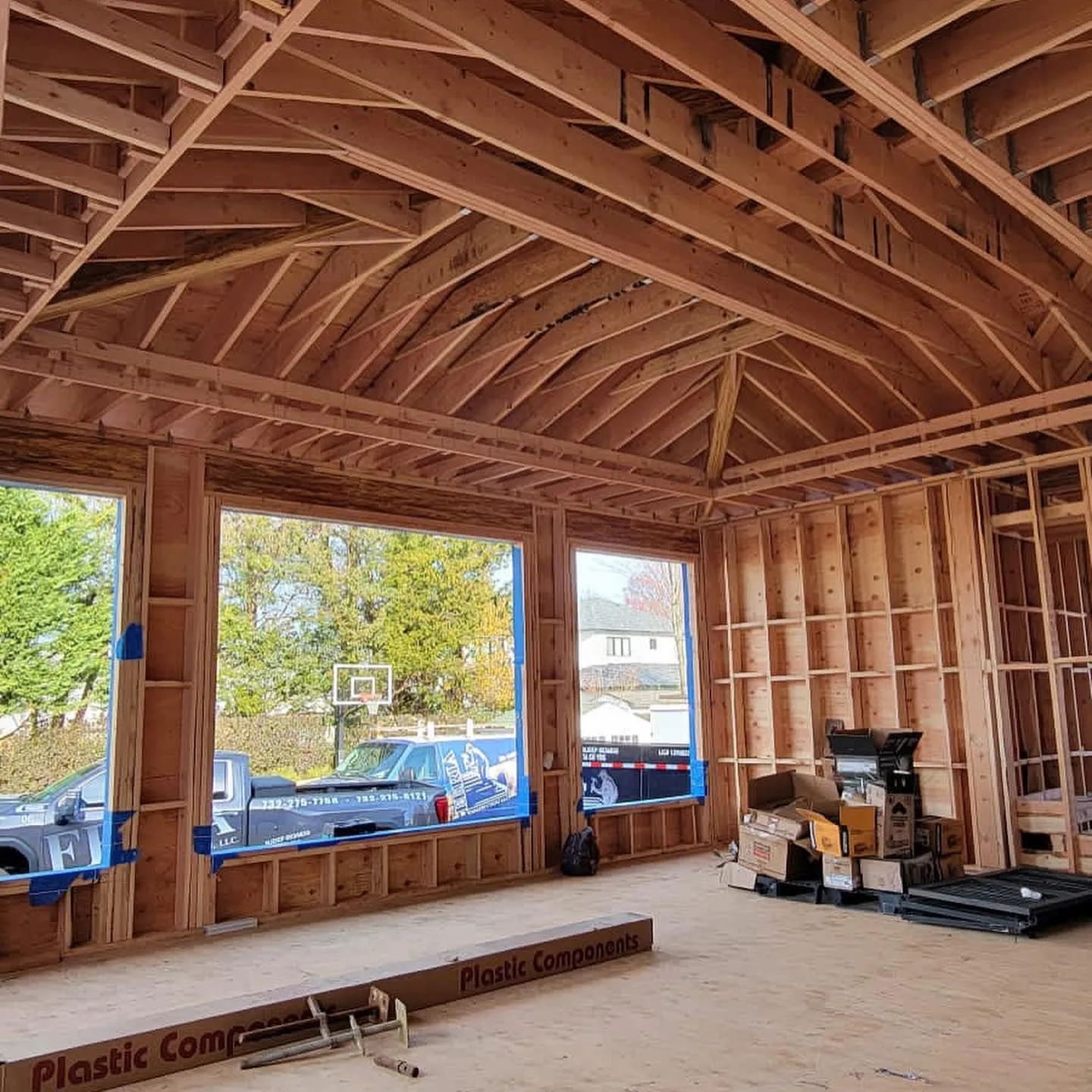 Interior of a house under construction with exposed wooden framing and large window openings