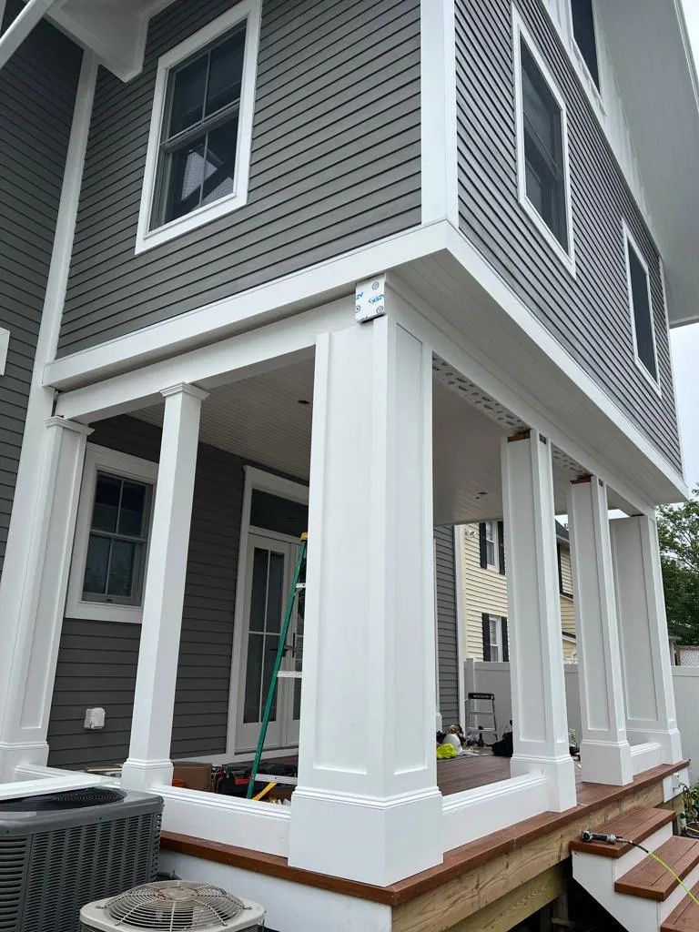 Gray house exterior with white porch columns and steps under construction