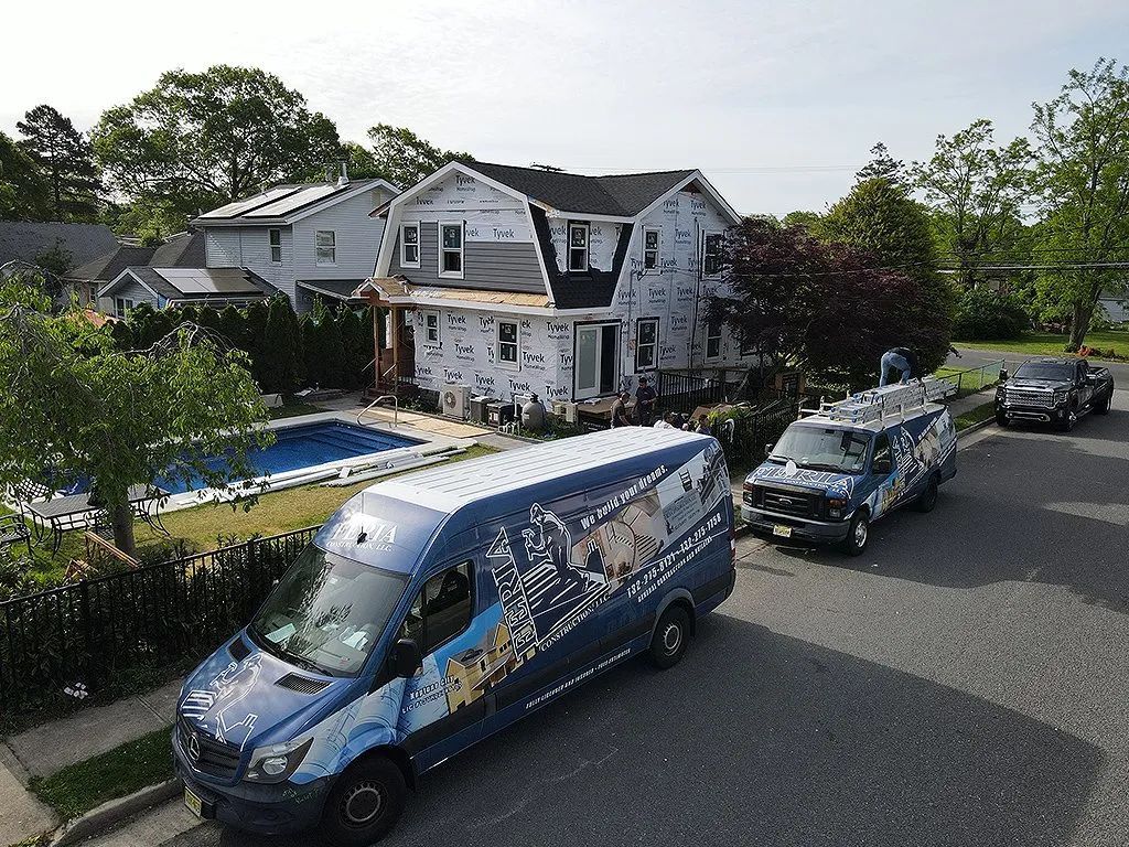 Blue van parked on a residential street in front of a damaged two-story house
