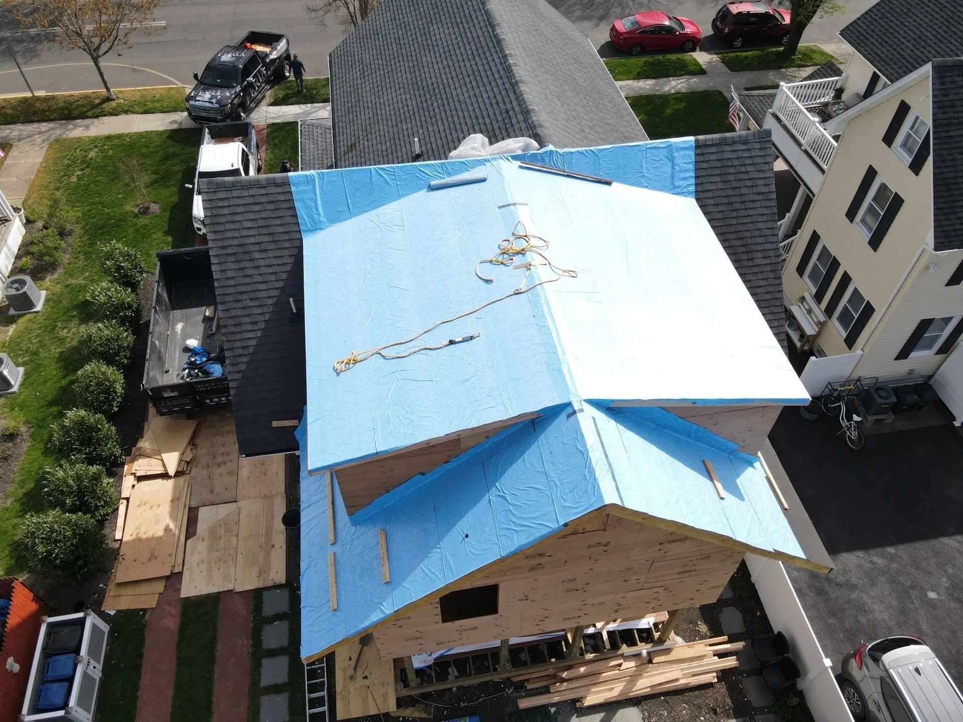 Aerial view of a house with a blue tarp-covered roof in a residential neighborhood.