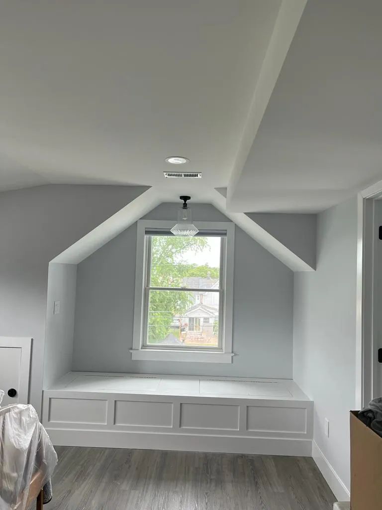 Gray attic bedroom with built-in drawers, centered window, sloped ceiling, and recessed lights