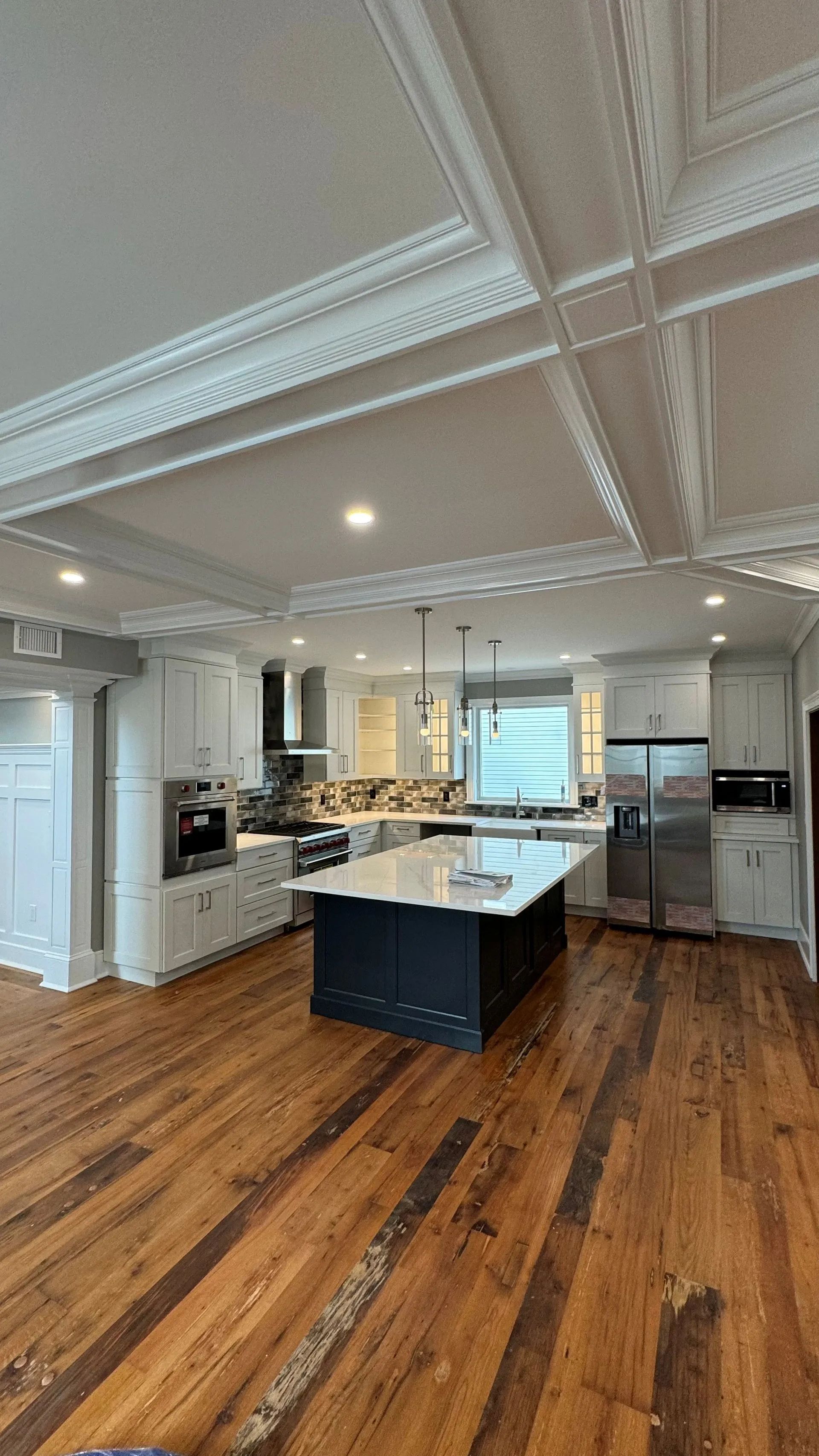 Bright modern kitchen with white cabinets, central island, and hardwood floors