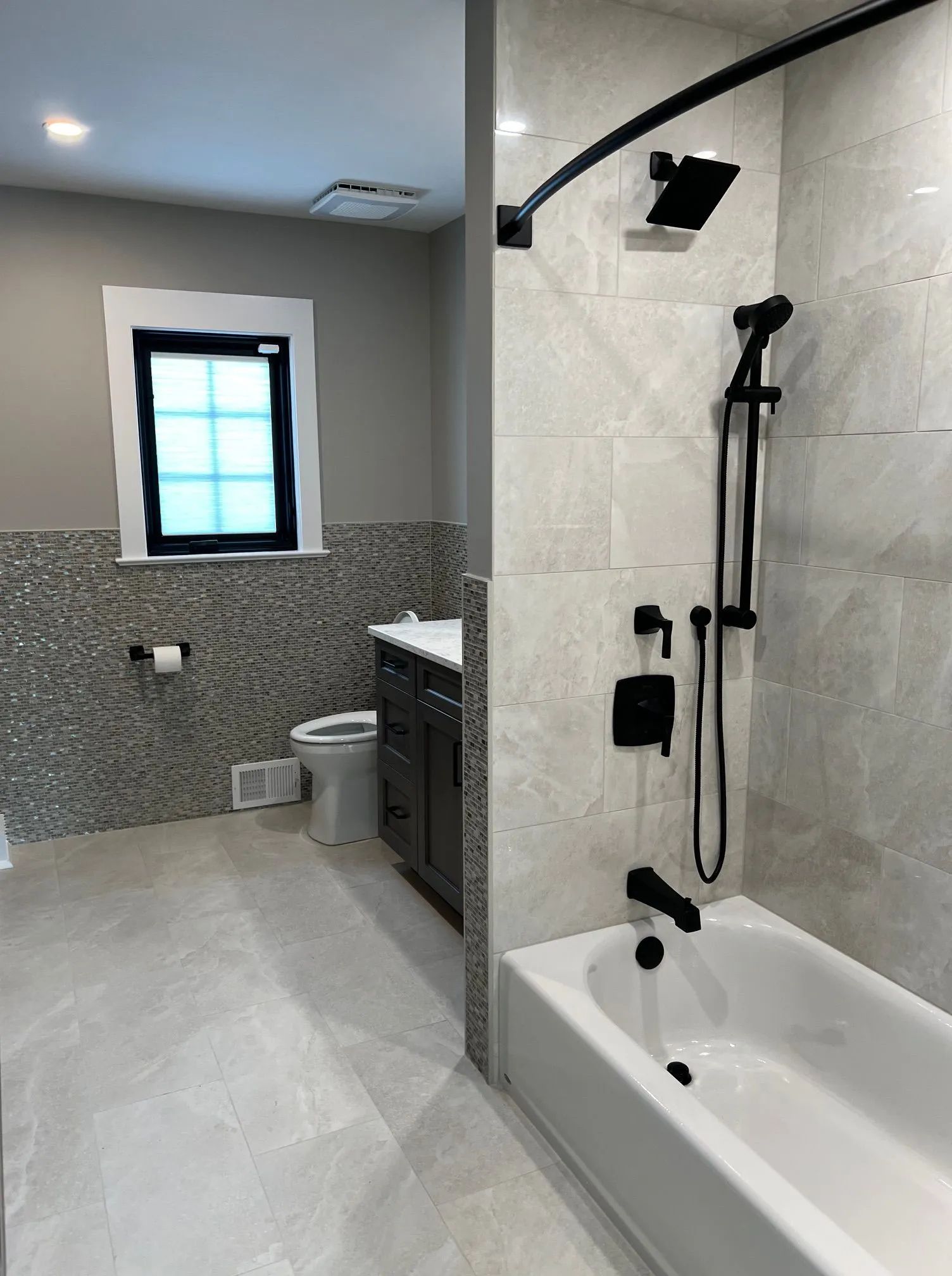 Accessible bathroom with walk-in shower, bathtub, and toilet in gray tile.