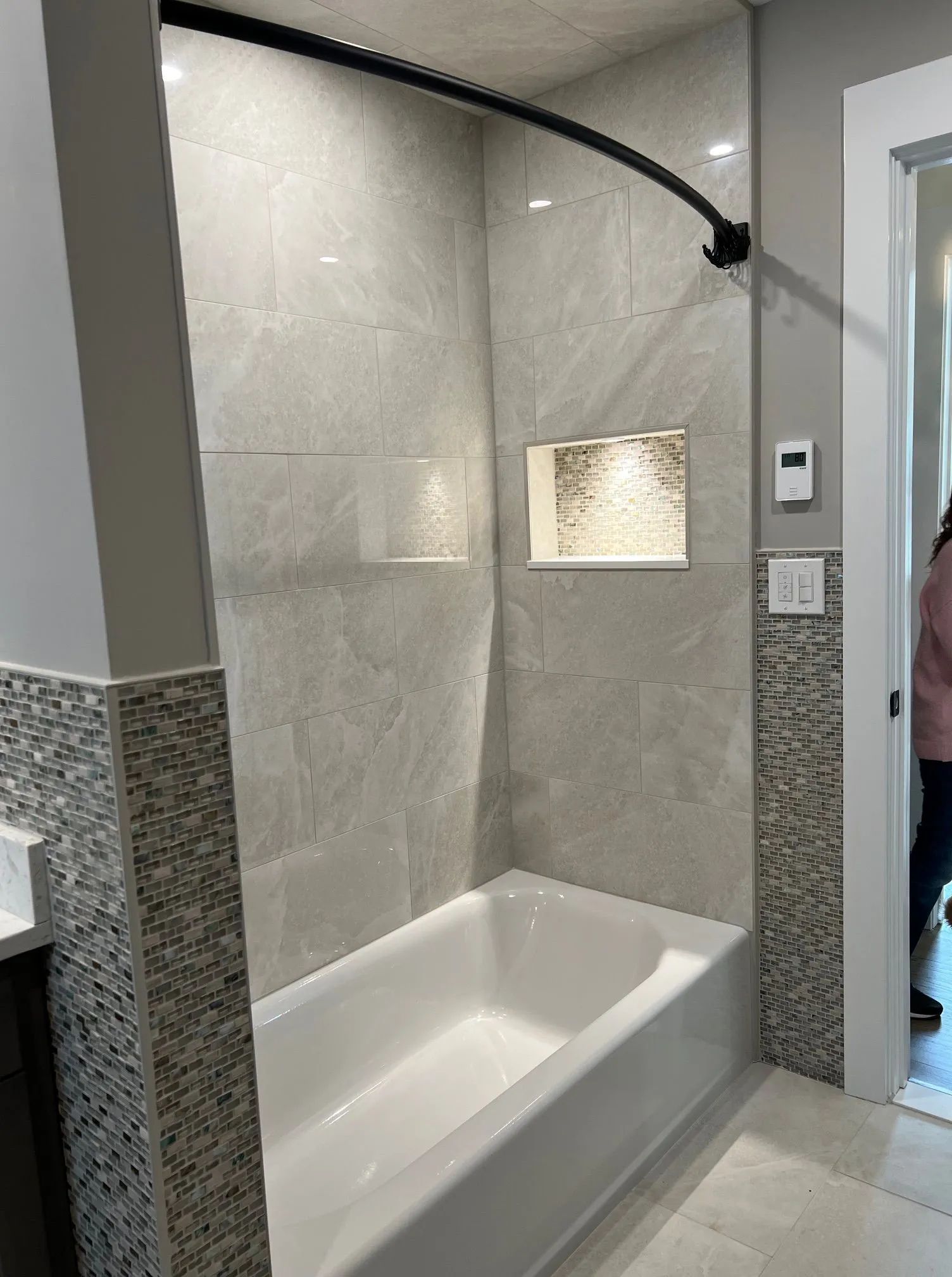 Accessible walk-in shower with built-in bench, tiled walls, and mosaic accent trim in a bathroom.