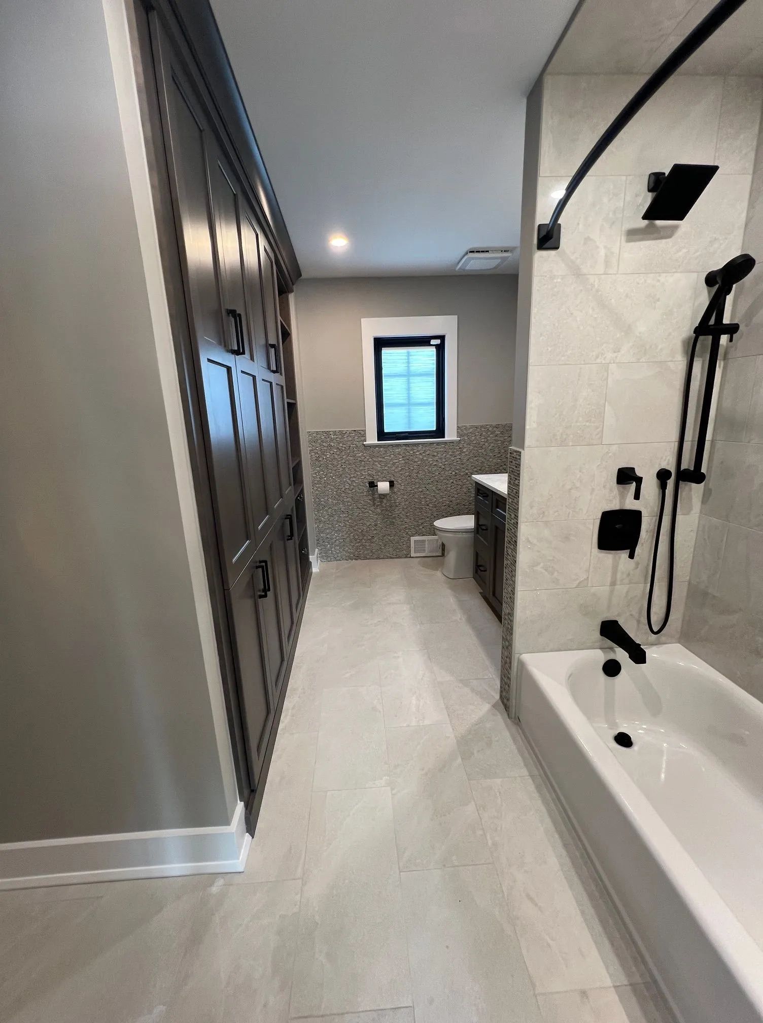Modern bathroom with walk-in shower, bathtub, tiled floor, and vanity area.